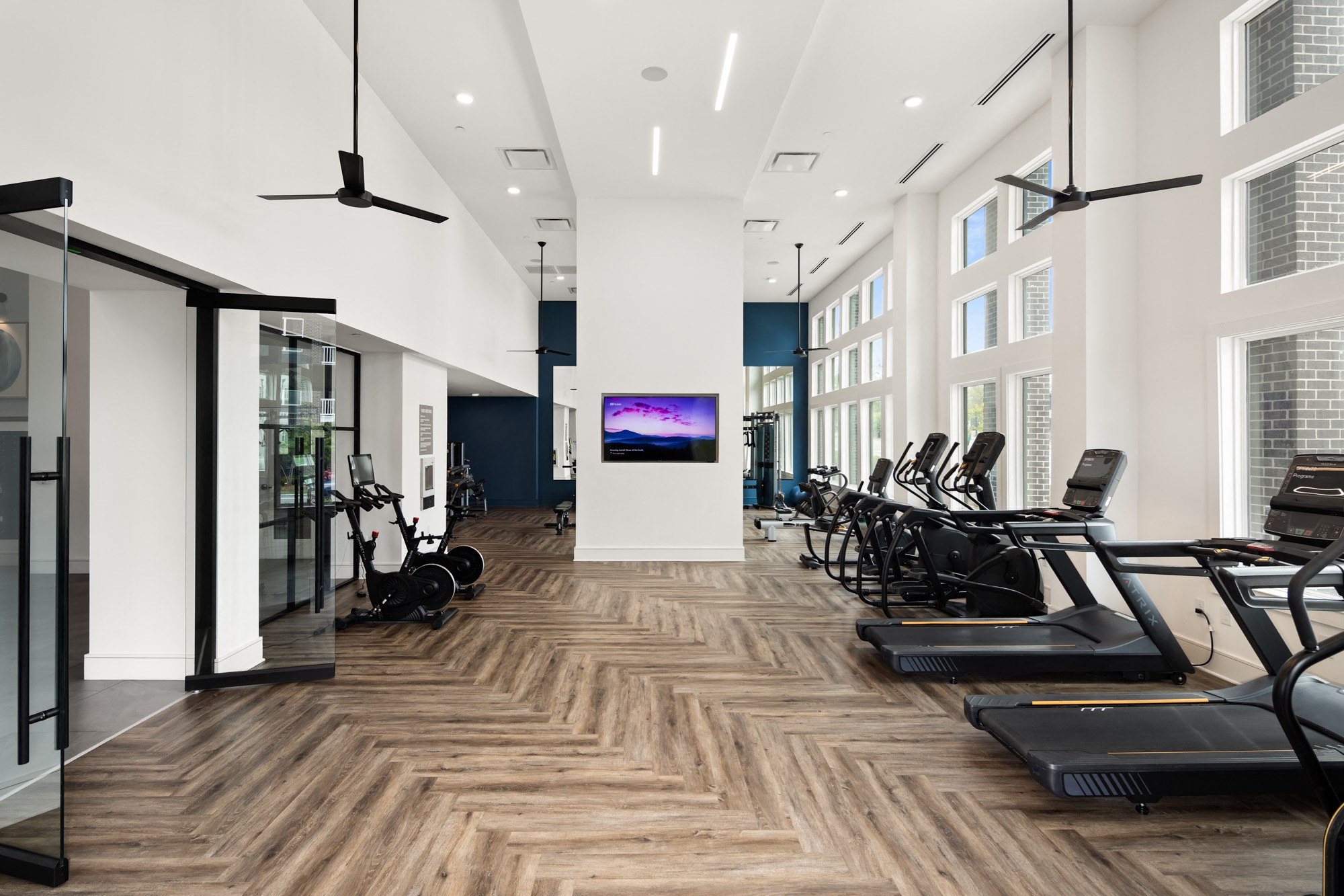 a gym with cardio machines and a tv on the wall